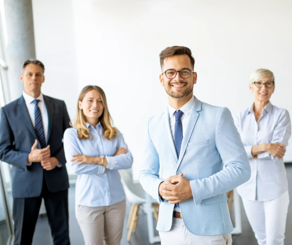 Cztery osoby w różnym wieku, które są zadowolone i uśmiechnięte ponieważ nawiązały współpracę z OZE